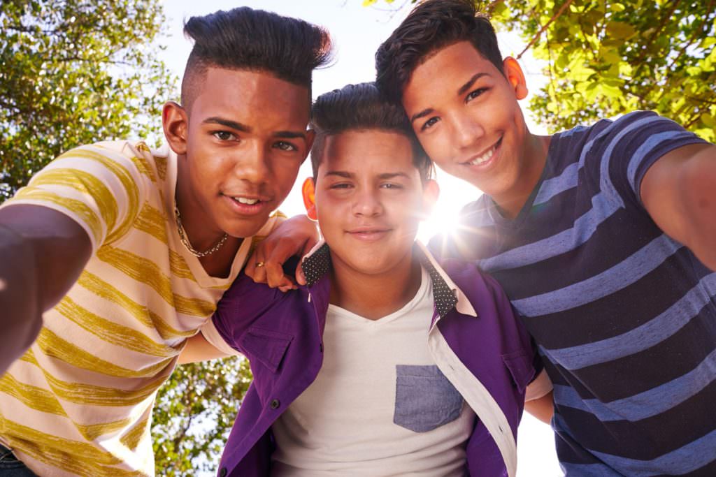 Youth culture young people group of male friends multi-ethnic teens outdoors teenagers together in park. Portrait of happy boys smiling kids looking at camera. Slow motion