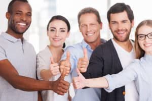 Group of cheerful business people in casual wear standing close to each other and showing their thumbs up